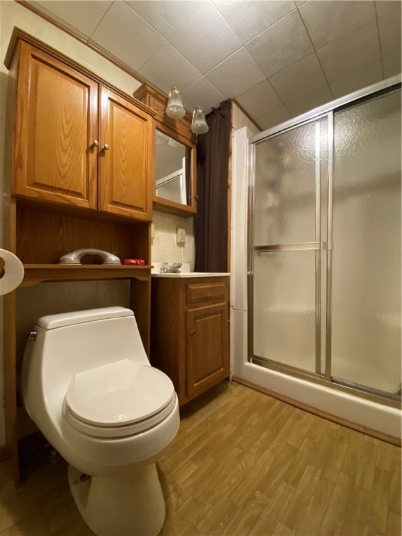 bathroom with vanity, toilet, hardwood / wood-style flooring, and walk in shower