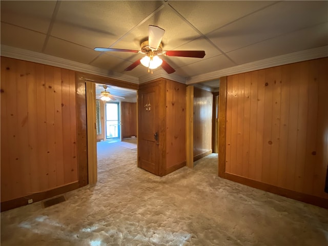 unfurnished room featuring wooden walls, ornamental molding, and ceiling fan