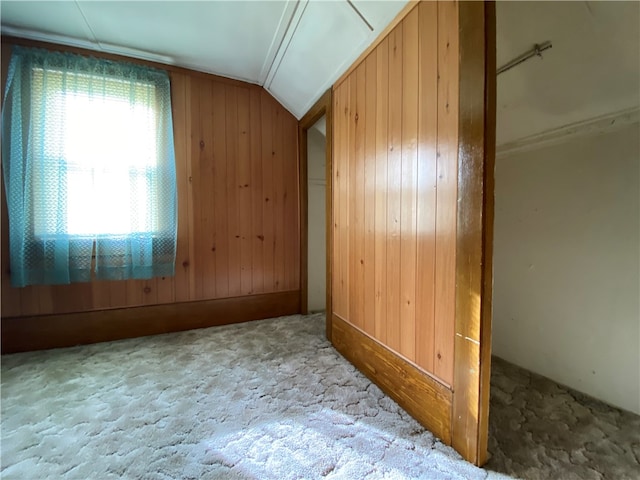 additional living space with wood walls, carpet floors, and lofted ceiling