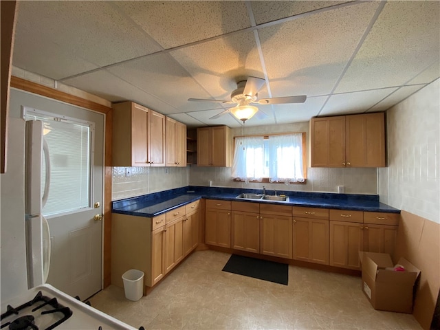 kitchen featuring ceiling fan, sink, a paneled ceiling, light tile patterned floors, and backsplash