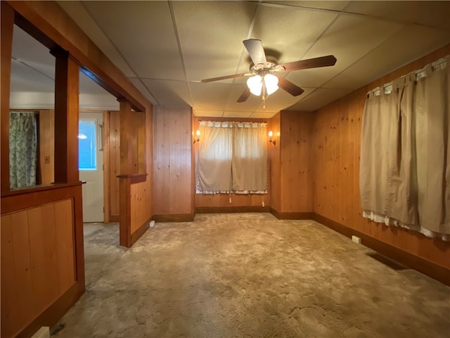 spare room featuring light colored carpet, wooden walls, and ceiling fan