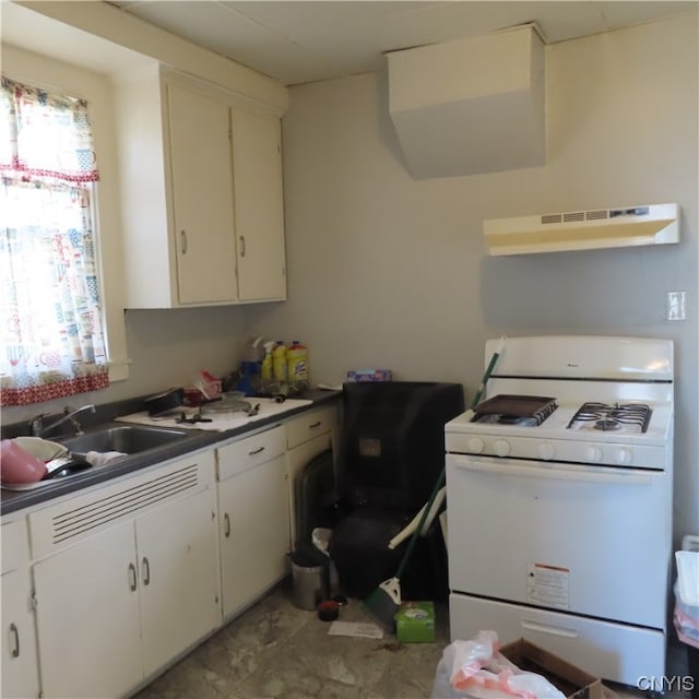 kitchen with light tile patterned flooring, wall chimney range hood, white cabinets, gas range gas stove, and sink