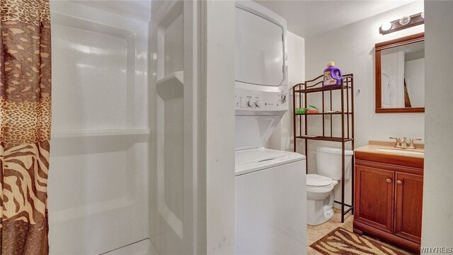 bathroom with tile patterned floors, vanity, a shower, toilet, and stacked washer / drying machine