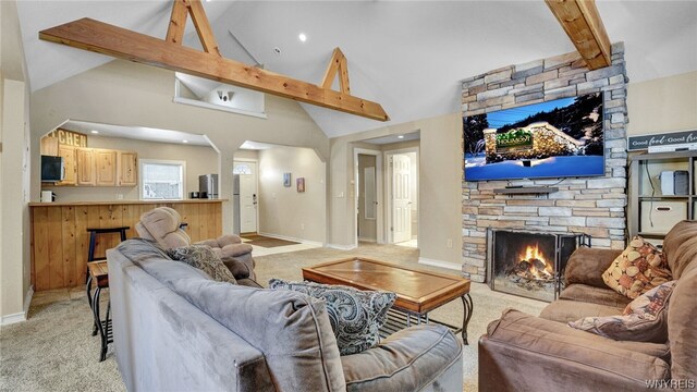 carpeted living room featuring a fireplace, beamed ceiling, and high vaulted ceiling