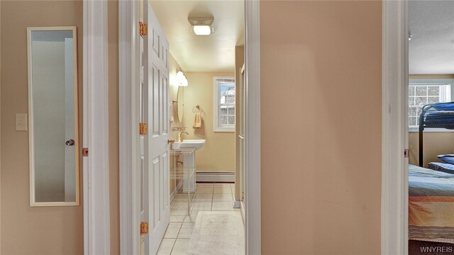 hall featuring light tile patterned flooring, sink, and a baseboard heating unit