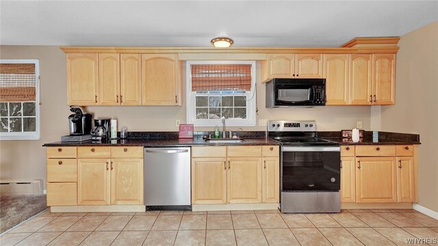 kitchen featuring sink, light tile patterned floors, baseboard heating, light brown cabinetry, and appliances with stainless steel finishes