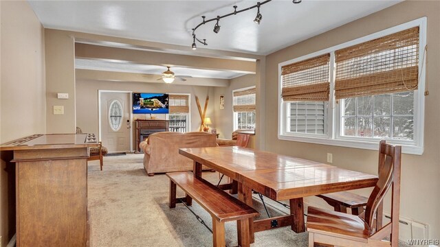 dining area featuring light carpet, rail lighting, a baseboard radiator, and ceiling fan