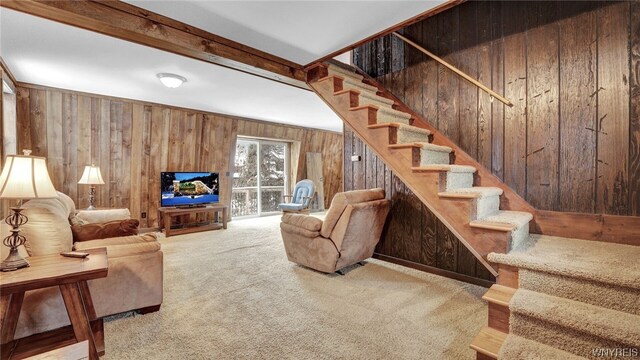 living room featuring beam ceiling, wooden walls, and carpet