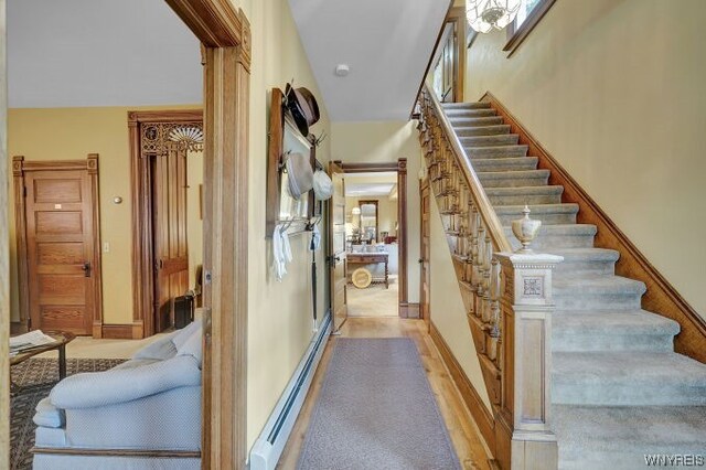 stairs featuring hardwood / wood-style floors and a baseboard heating unit