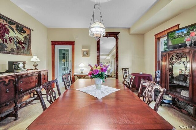 carpeted dining space with an inviting chandelier