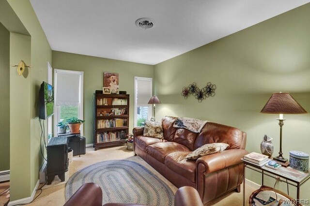 living room featuring plenty of natural light, light colored carpet, and a baseboard radiator