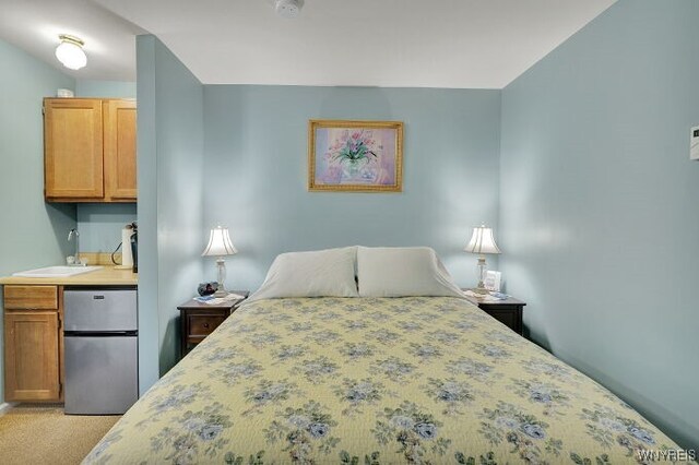 carpeted bedroom featuring sink and stainless steel refrigerator