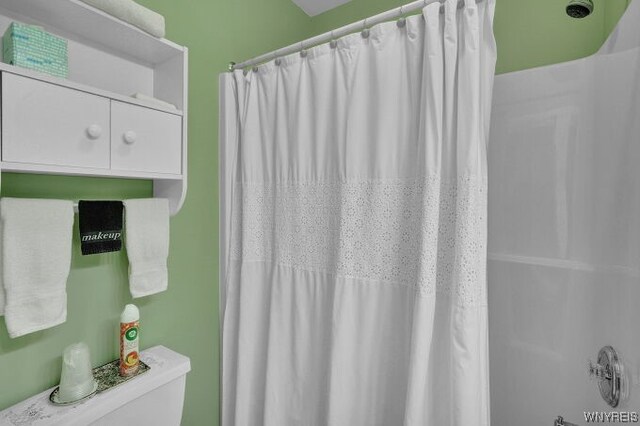 bathroom featuring toilet and shower / tub combo with curtain