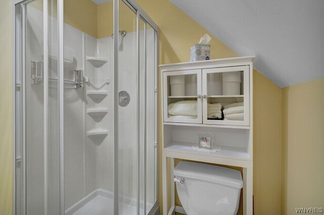 bathroom with toilet, an enclosed shower, and lofted ceiling