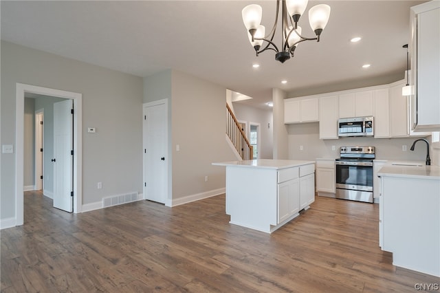 kitchen with white cabinetry, stainless steel appliances, a center island, pendant lighting, and sink