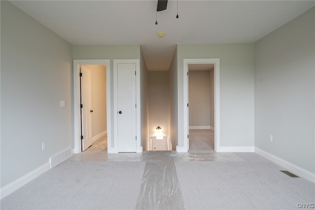 unfurnished bedroom featuring connected bathroom, ceiling fan, and light colored carpet