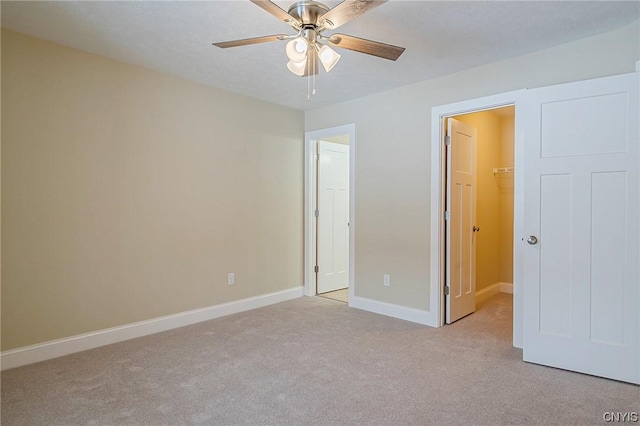 unfurnished bedroom featuring ceiling fan, light carpet, a spacious closet, and a closet