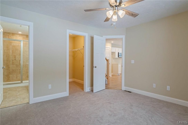 unfurnished bedroom featuring ceiling fan, light colored carpet, a closet, and a spacious closet