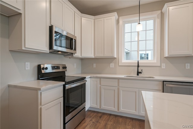 kitchen with white cabinets, appliances with stainless steel finishes, dark hardwood / wood-style flooring, sink, and hanging light fixtures