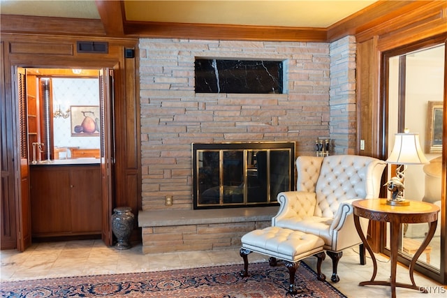 living area with beam ceiling and a stone fireplace