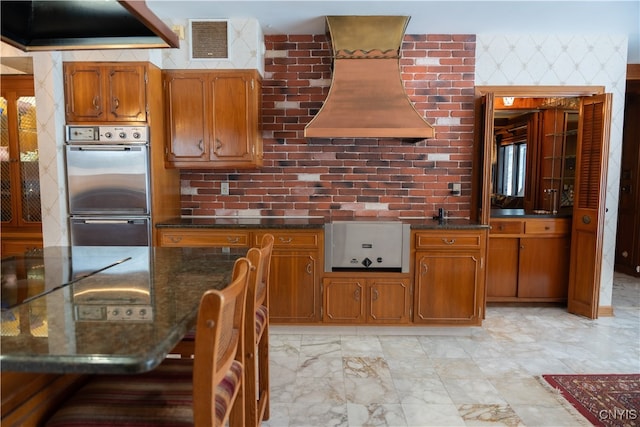 kitchen featuring double wall oven, extractor fan, and custom range hood