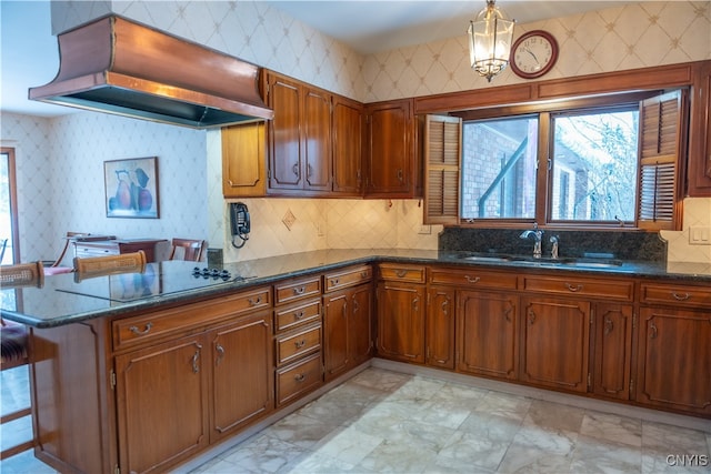 kitchen with sink, dark stone countertops, kitchen peninsula, premium range hood, and pendant lighting