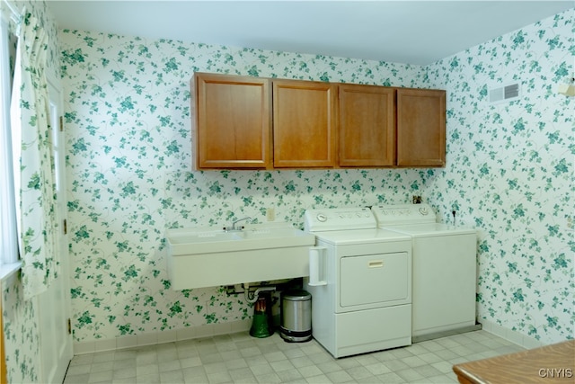 laundry room with sink, washing machine and clothes dryer, and cabinets