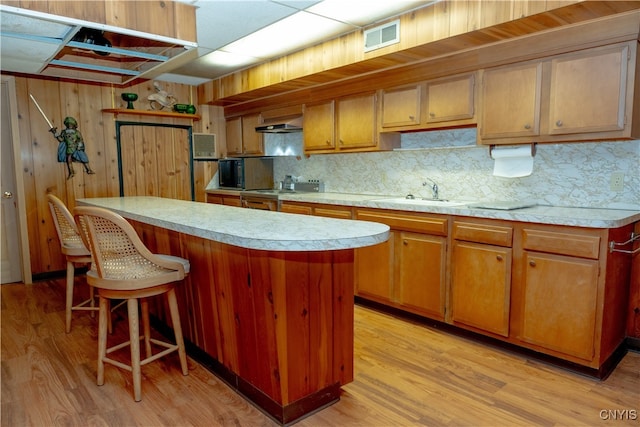 kitchen featuring sink, light wood-type flooring, tasteful backsplash, range, and a kitchen island