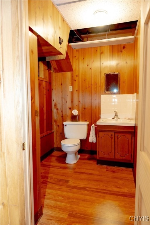 bathroom featuring toilet, vanity, wood walls, and hardwood / wood-style floors