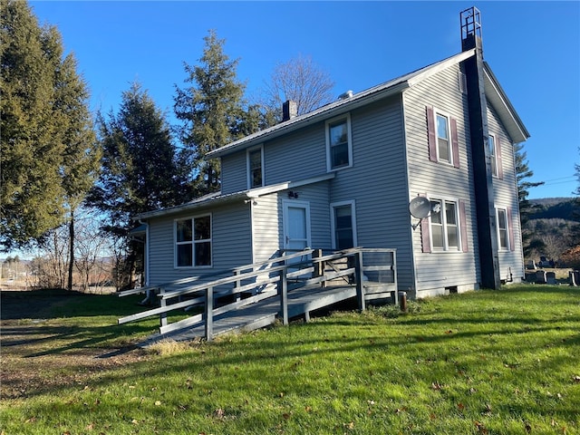 rear view of property featuring a lawn and a deck