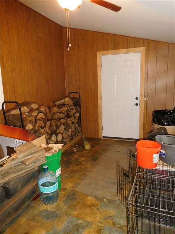 interior space with lofted ceiling, wood walls, and ceiling fan