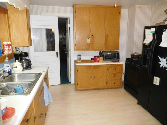 kitchen with black appliances, light hardwood / wood-style floors, and sink