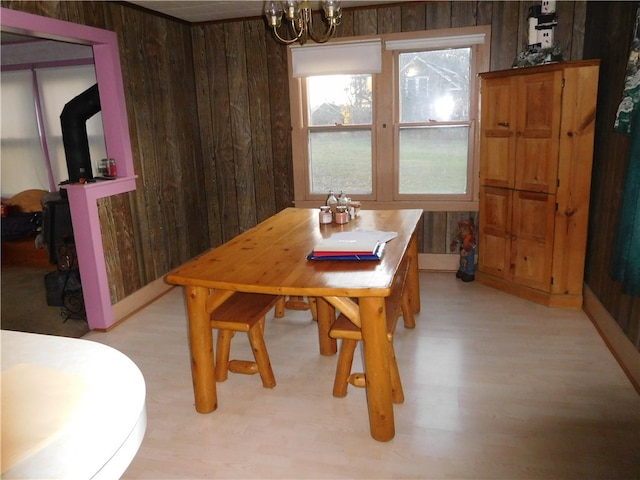 dining room with light hardwood / wood-style floors, wood walls, and a notable chandelier