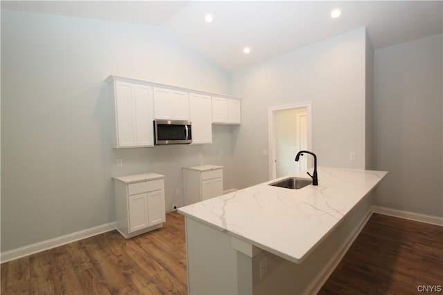 kitchen with white cabinetry, kitchen peninsula, sink, and dark hardwood / wood-style floors