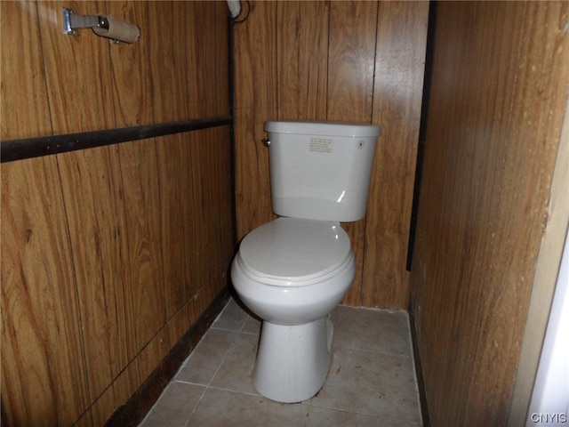 bathroom with wood walls, tile floors, and toilet