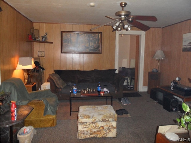 living room with wooden walls, ceiling fan, and carpet