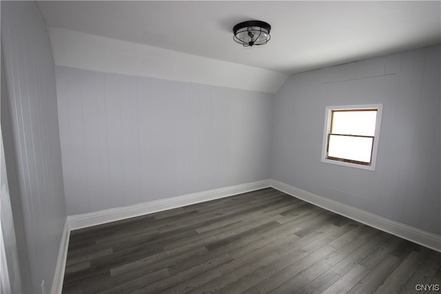 unfurnished room featuring lofted ceiling and dark hardwood / wood-style flooring