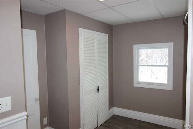 unfurnished bedroom featuring dark hardwood / wood-style flooring, a closet, and a drop ceiling