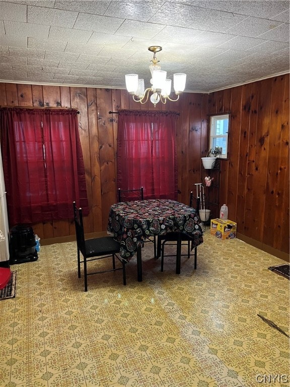 dining area with wood walls and a notable chandelier