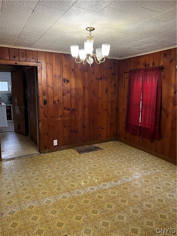 unfurnished room with wooden walls and an inviting chandelier