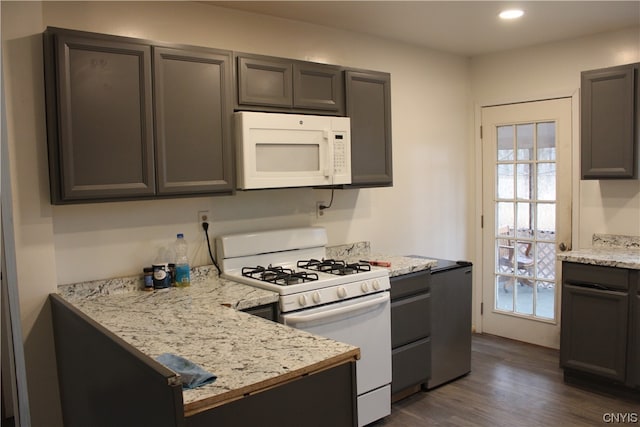 kitchen with light stone counters, dark brown cabinetry, white appliances, and dark hardwood / wood-style floors