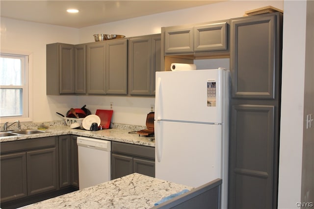 kitchen with gray cabinets, white appliances, sink, and light stone countertops