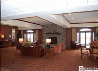 carpeted living room with a stone fireplace