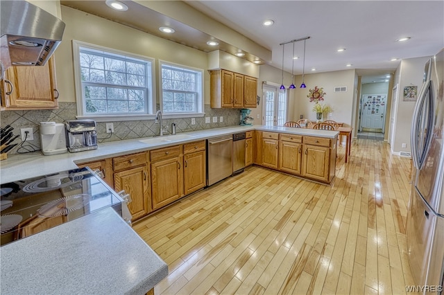 kitchen with tasteful backsplash, wall chimney exhaust hood, light hardwood / wood-style floors, and decorative light fixtures