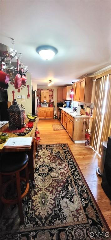 kitchen with sink, stainless steel fridge, and light wood-type flooring