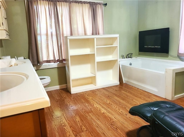 bathroom with hardwood / wood-style flooring, toilet, sink, and a tub to relax in