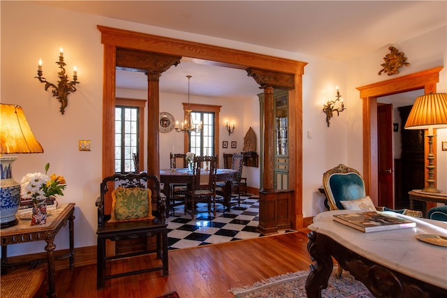 office area featuring dark hardwood / wood-style flooring, a notable chandelier, and decorative columns