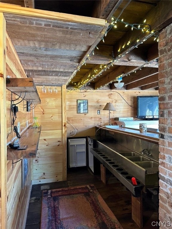 interior space featuring brick wall, wooden walls, and sink