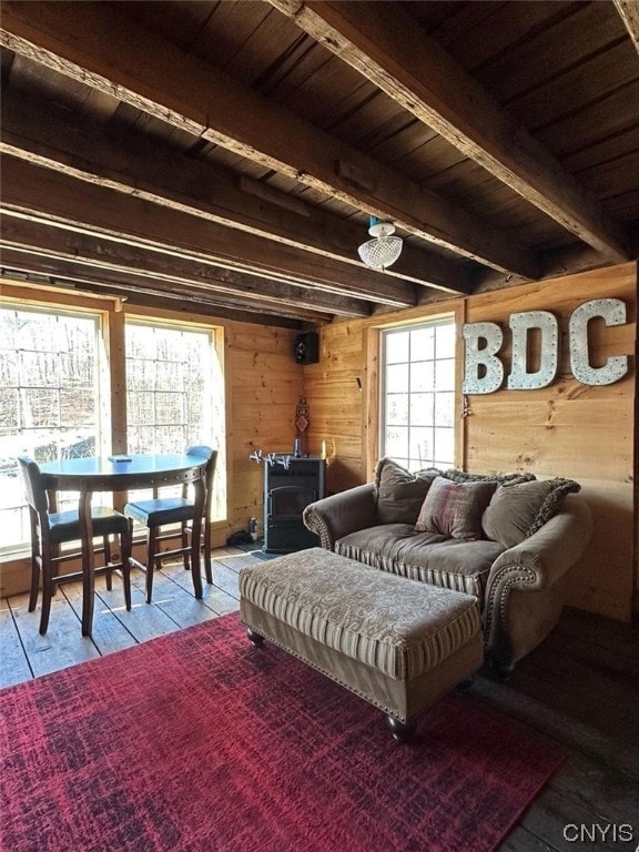 living room featuring beamed ceiling, wood ceiling, a wood stove, and wood walls