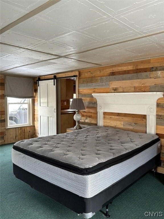 unfurnished bedroom with carpet flooring, wooden walls, and a barn door